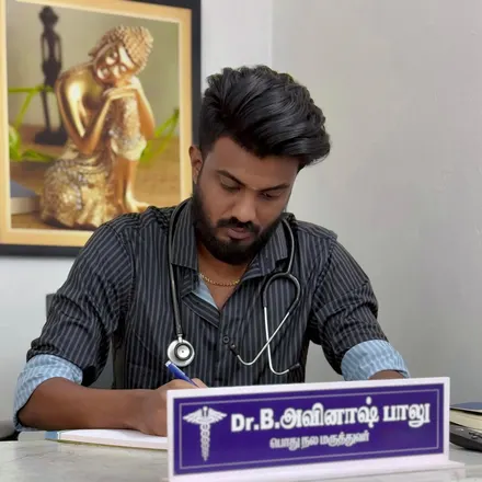 Dr. Avinash Balu writing at his desk, with his nameplate in front of him