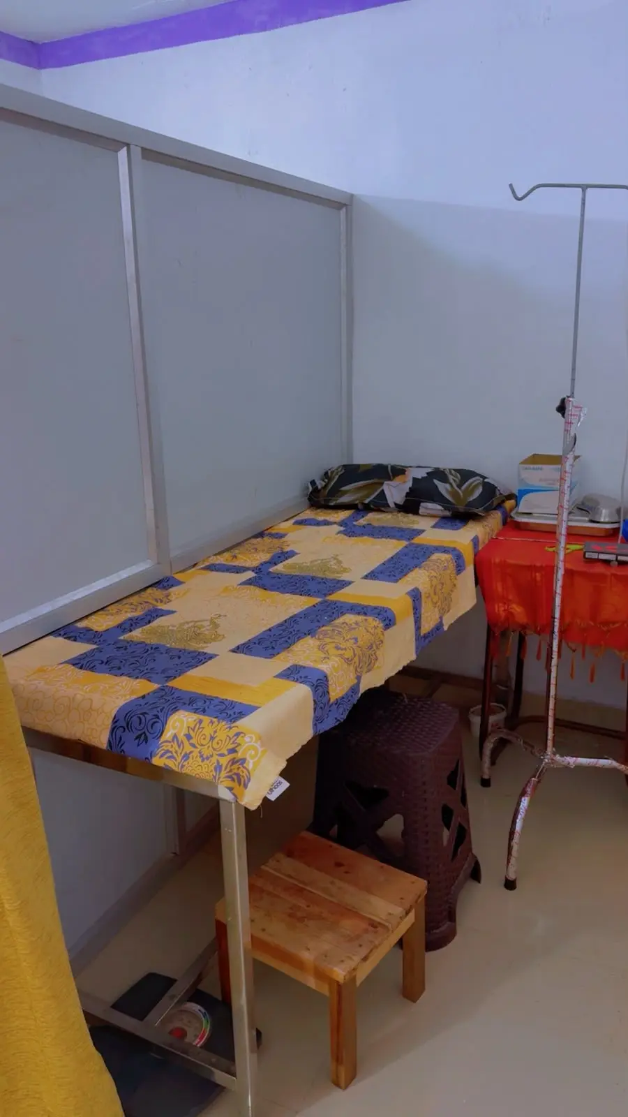 A treatment bed with a drip stand and a small table of supplies