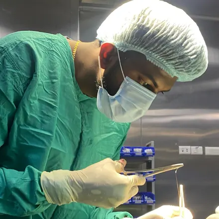 Dr. Avinash Balu in surgical scrubs, cap and mask, working with an instrument